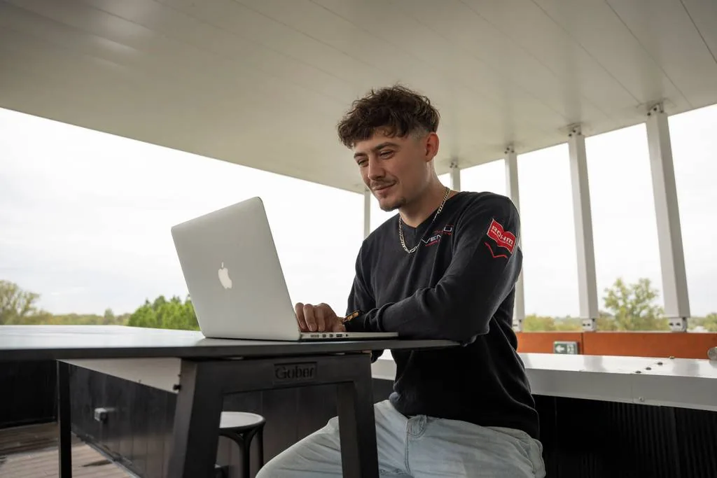 Un étudiant travaille sur son ordinateur portable sur la terrasse du campus